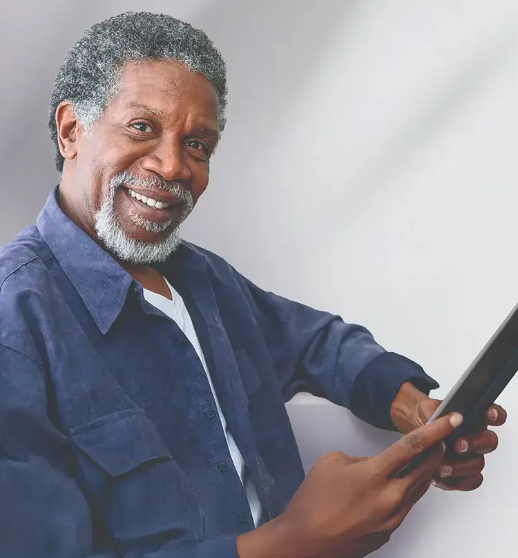 Image of an older black man holding a tablet and smiling at the camera
