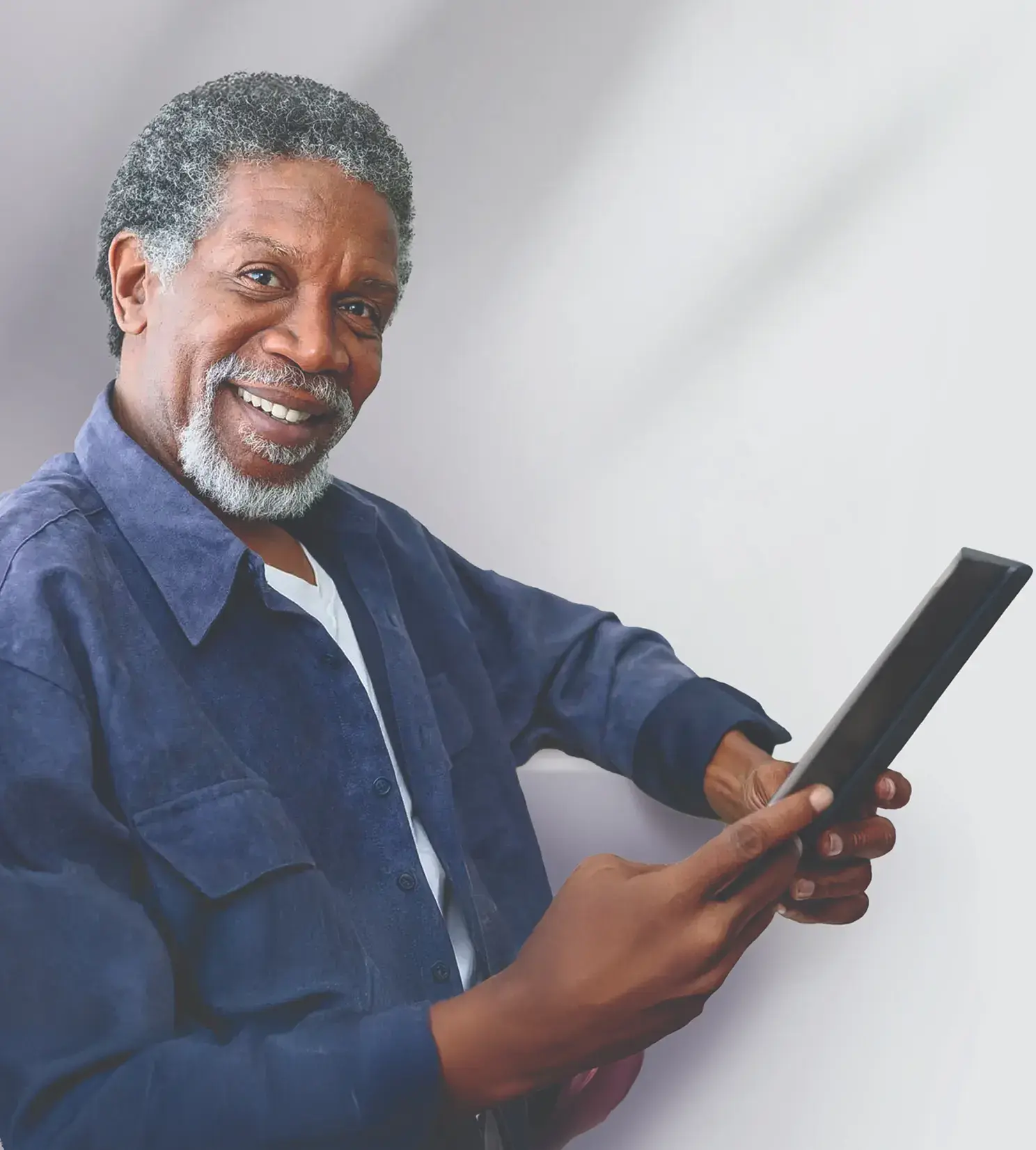 Image of an older black man holding a tablet and smiling at the camera